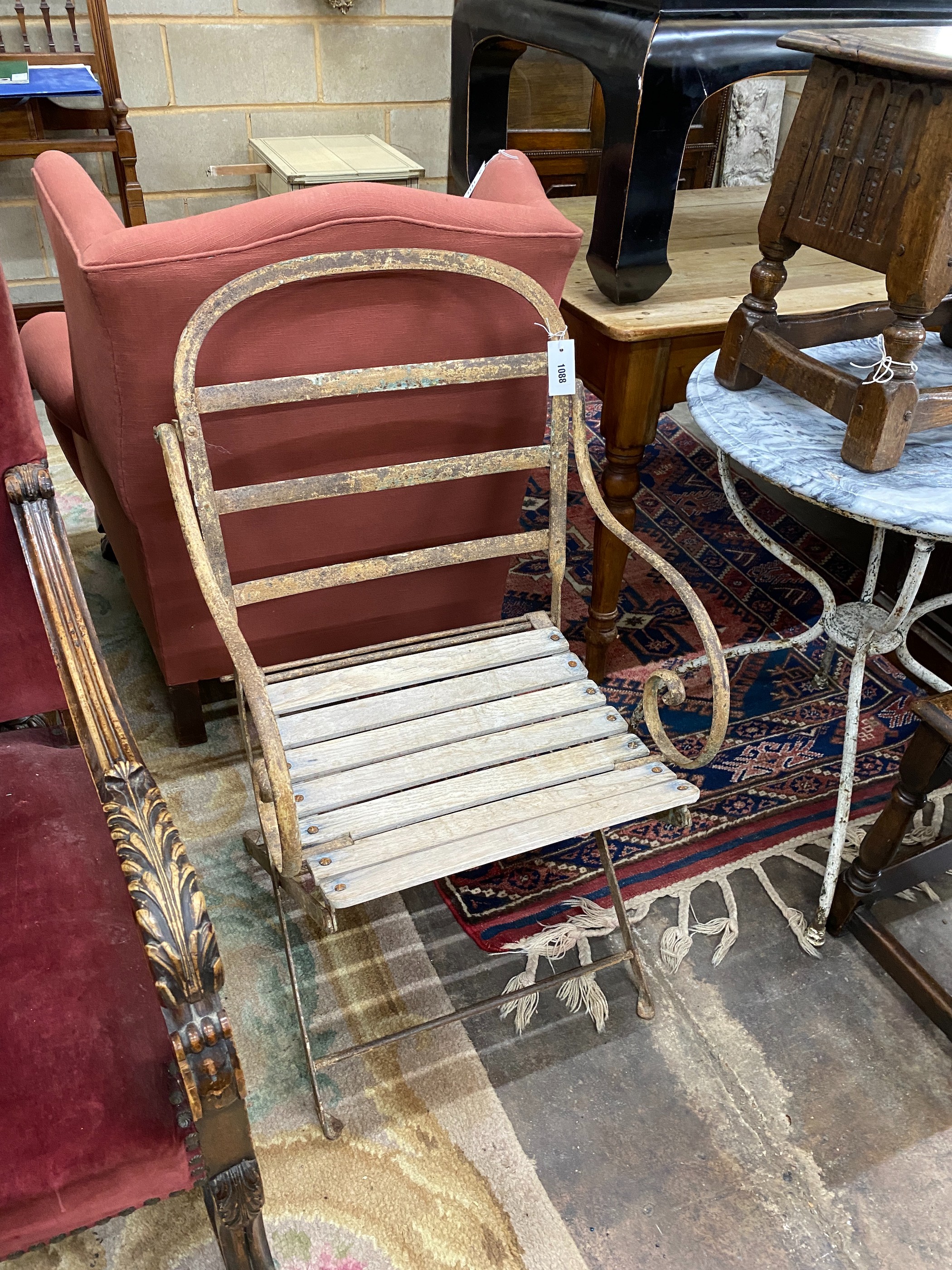 A wrought iron folding garden chair with slatted wood seat